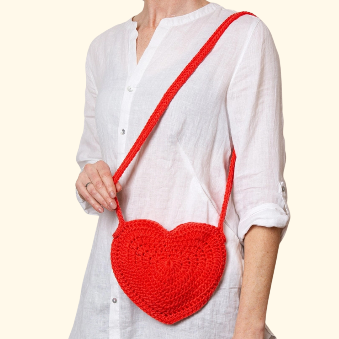 Model wearing the completed heart shaped crochet bag made with the Wool Couture Heart Bag Crochet Kit.