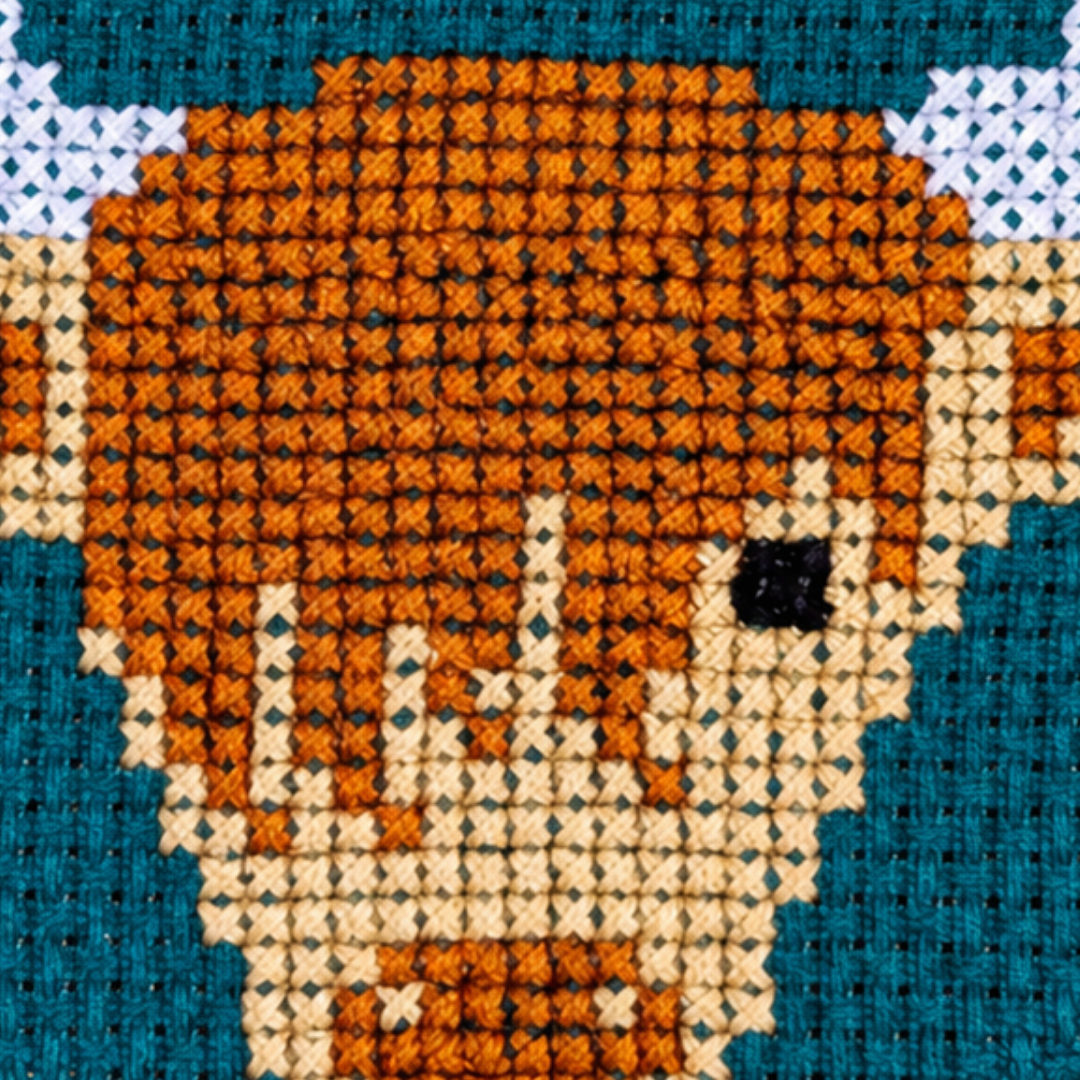 Close-up of the Highland Coo cross stitch design featuring a shaggy brown cow with horns on a blue background.