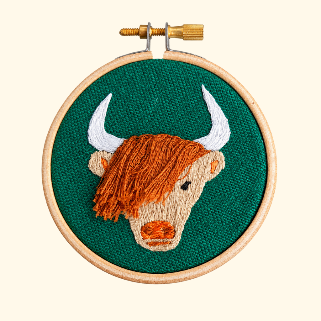 Finished Highland Coo Mini Embroidery Kit by Paraffle displayed in a wooden embroidery hoop.