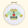 Finished I Love Dogs cross stitch featuring a mint green jumper with colourful details and “I ♥ DOGS” lettering, displayed in a bamboo embroidery hoop.