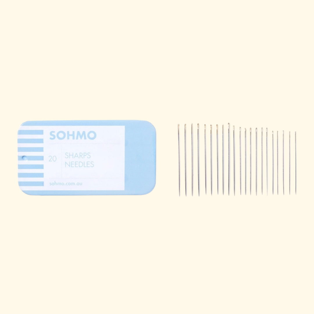 A set of 20 sewing sharps needles from the brand SOHMO, shown with their light blue and white cardboard packaging on a solid pale cream background.