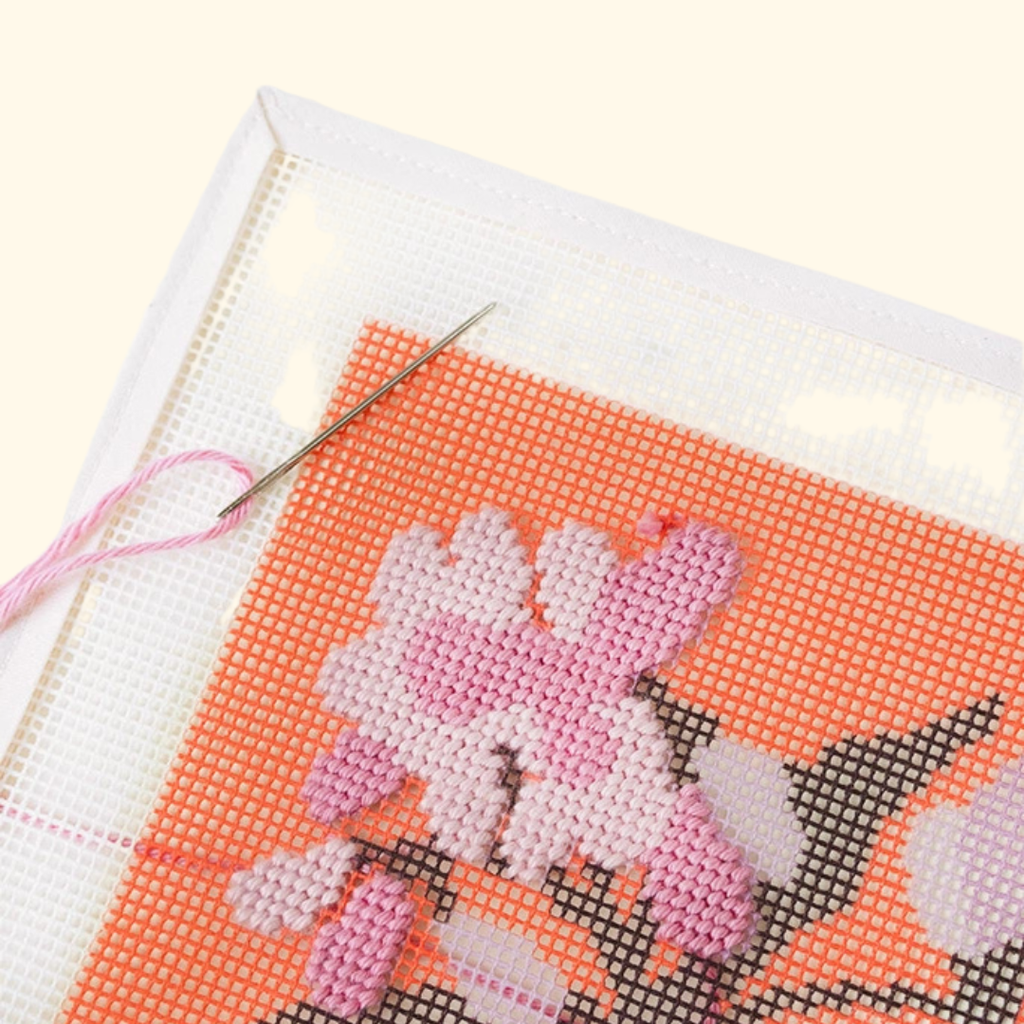 Joe Pye Weed floral needlepoint design being stitched on pre-printed canvas