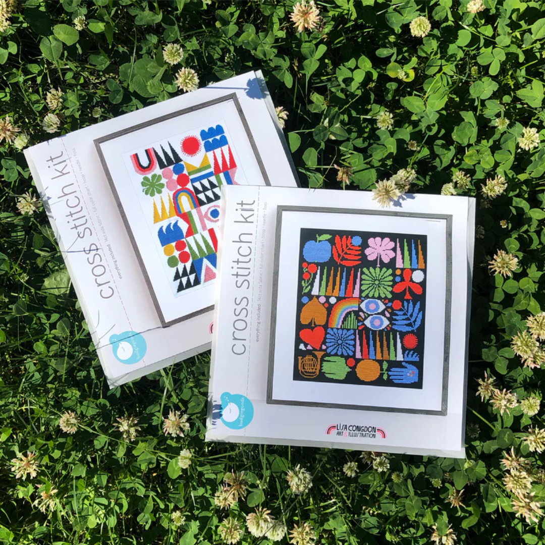 Joyful Grid Cross Stitch Kit by Budgiegoods showing the kit packaging and completed stitched design outdoors.
