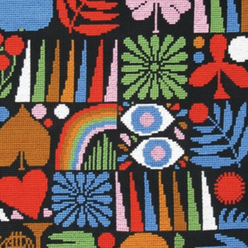 Close up of the Joyful Grid cross stitch showing textured stitches and vibrant floral and geometric details.