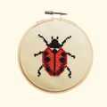 Completed ladybird cross stitch design stitched in a bamboo embroidery hoop by Cotton Clara.