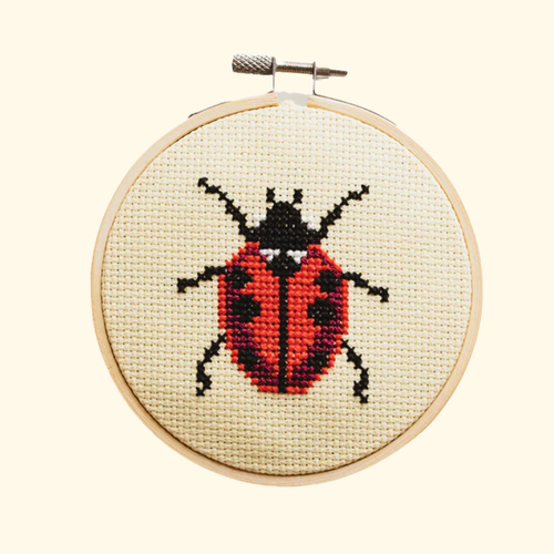 Completed ladybird cross stitch design stitched in a bamboo embroidery hoop by Cotton Clara.