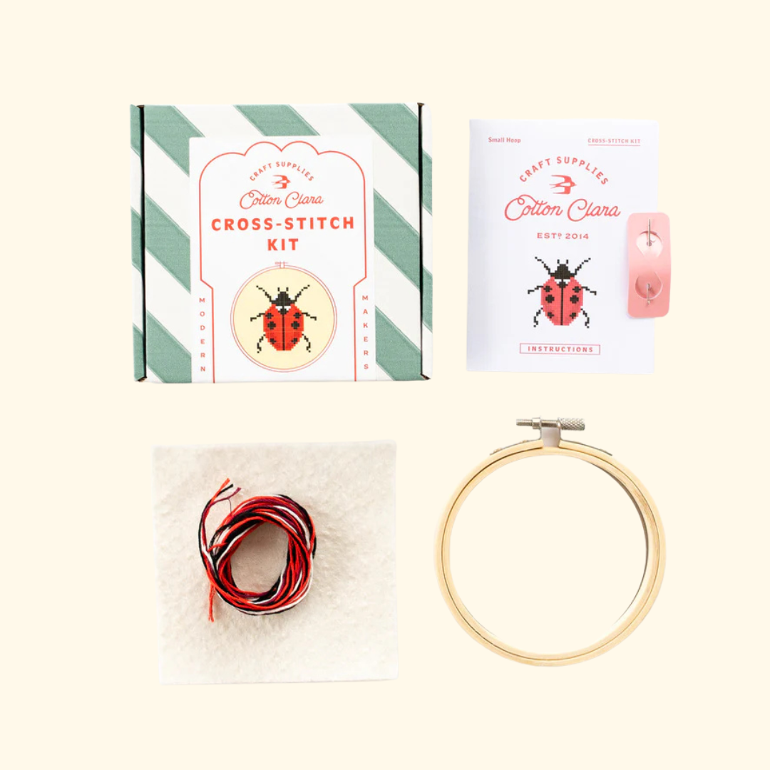 Contents of the Cotton Clara Ladybird Cross Stitch Kit including hoop, Aida fabric, threads, needle and instructions.