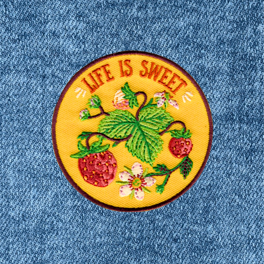Life Is Sweet embroidered iron on patch by Anna Seed Art applied to blue denim fabric.