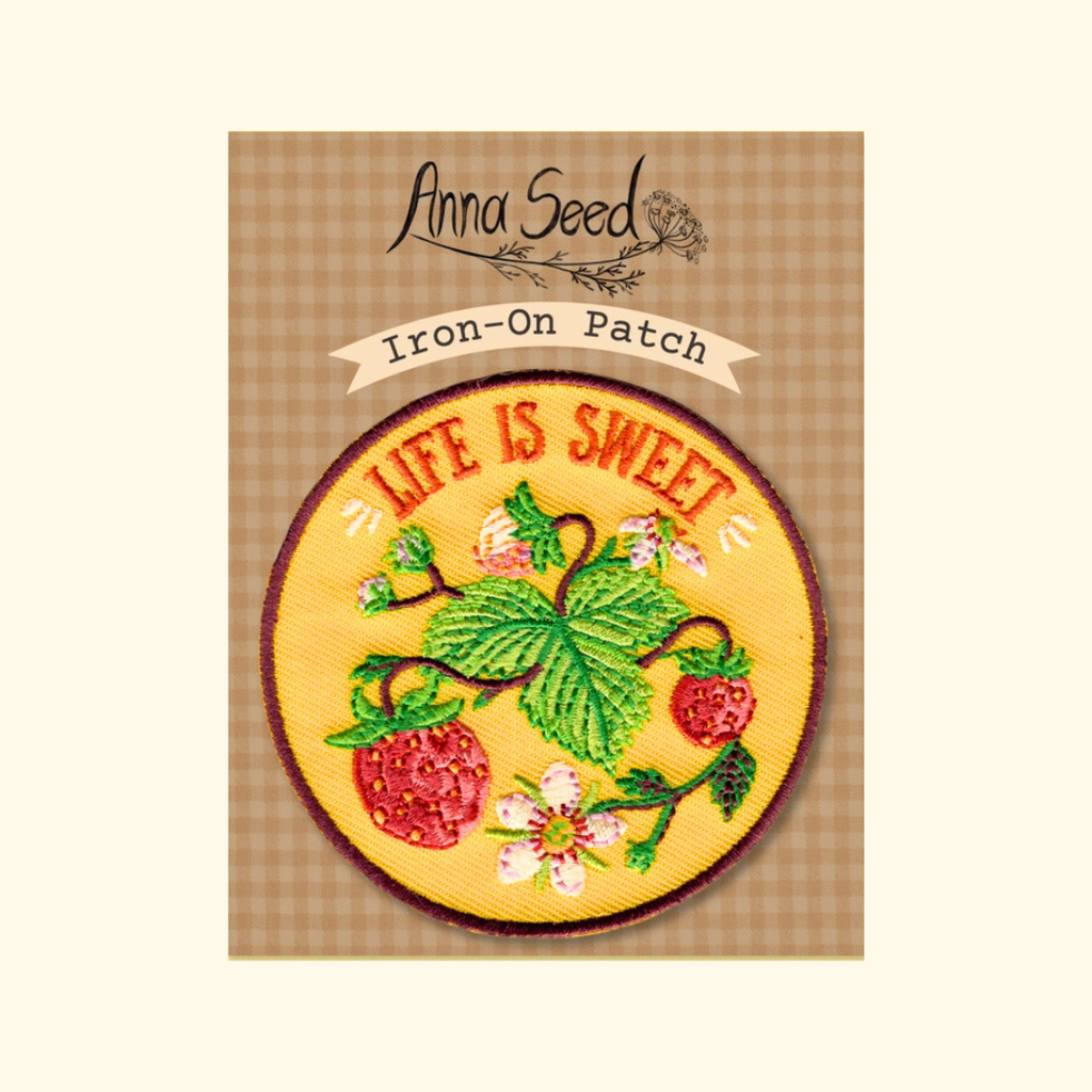 Packaged Life Is Sweet embroidered iron on patch by Anna Seed Art displayed on its backing card.