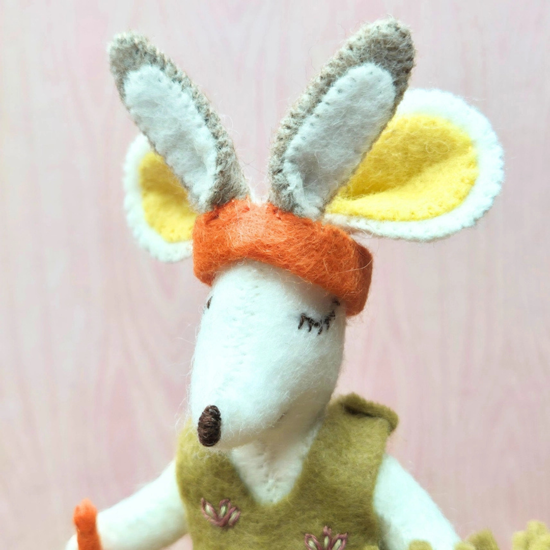 Close-up of the handmade felt mouse showing embroidered facial details, large ears and a tiny felt hat.
