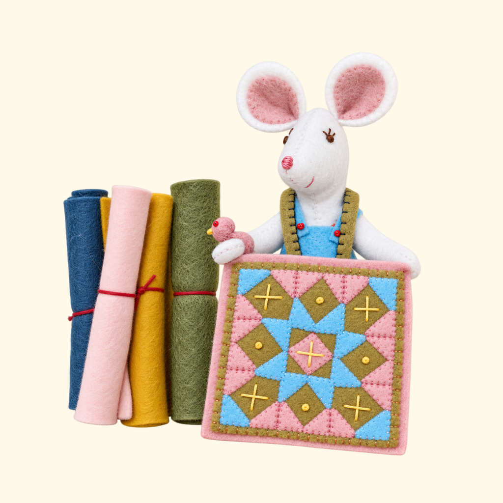 Completed felt mouse holding a colourful patchwork quilt, with sewing accessories and wool-mix felt.