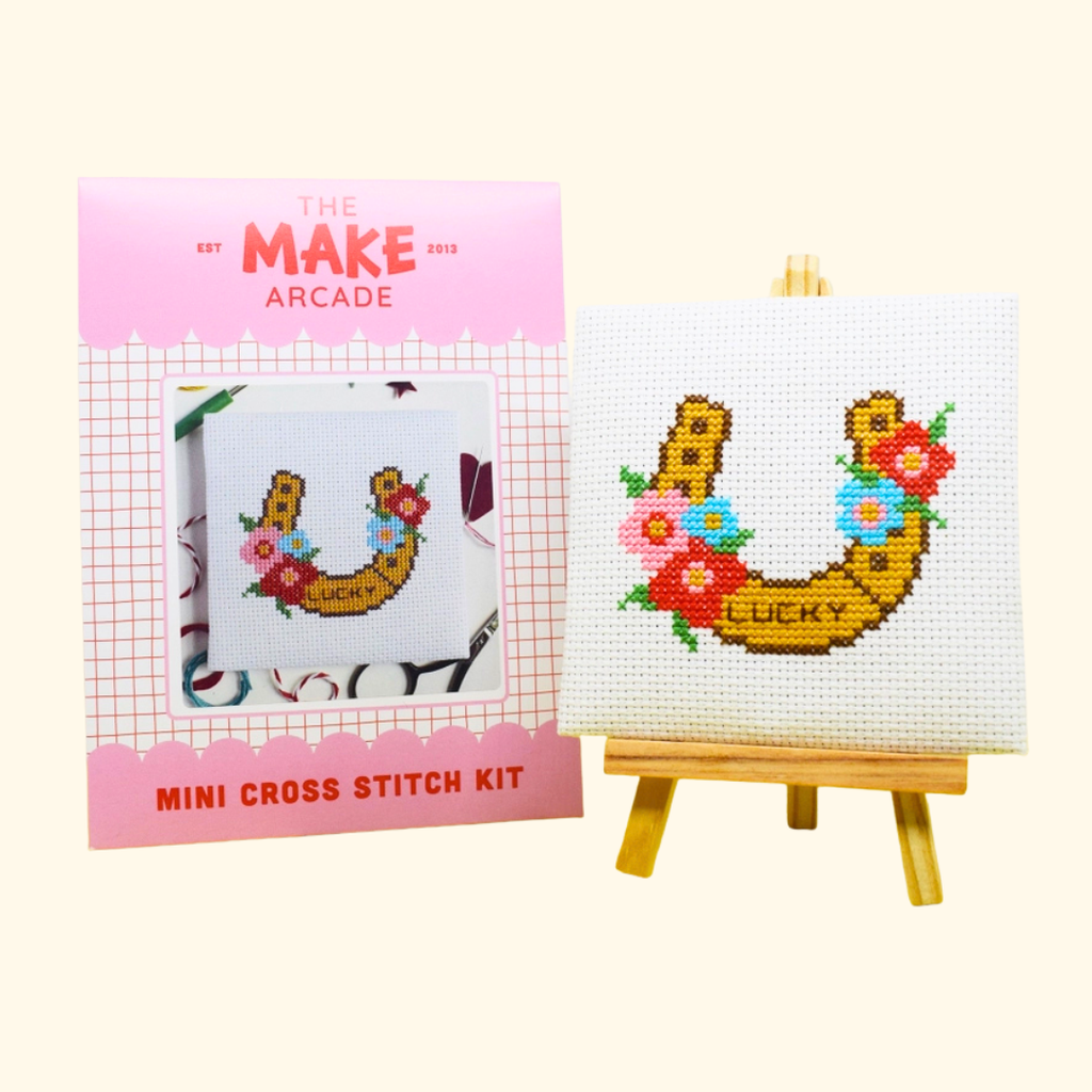 Lucky Horseshoe Mini Cross Stitch Kit by The Make Arcade with packaging and finished stitched design on a mini easel.