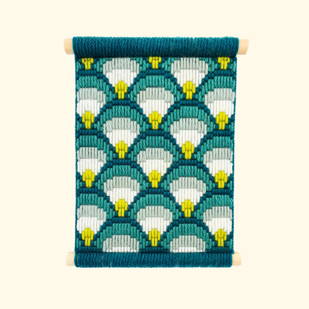 Completed bargello wall hanging featuring a teal, aqua and lime scallop pattern displayed in a wooden frame