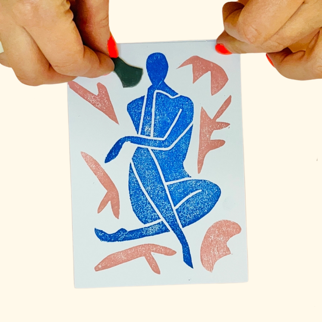 Finished Matisse-inspired lino print in blue and terracotta colours held up after printing by hand.