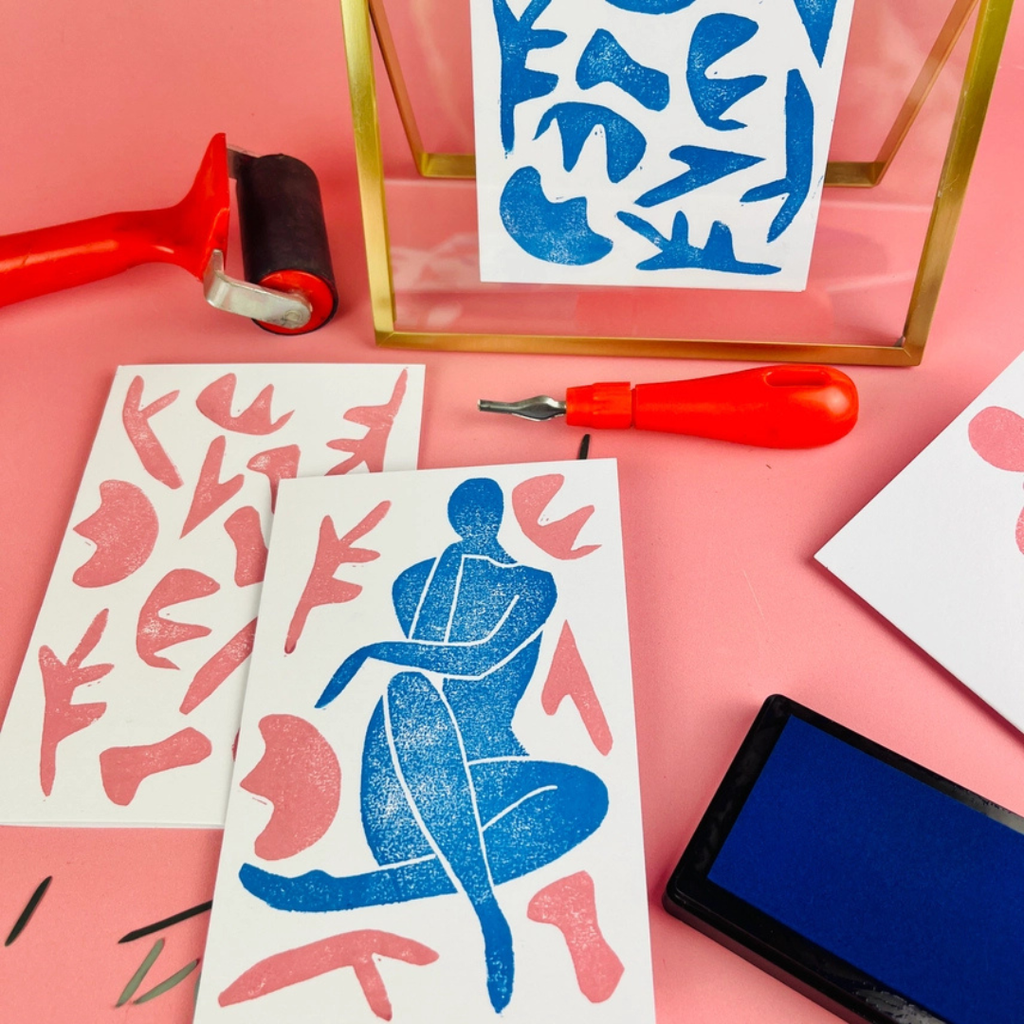 Matisse-inspired lino print alongside carving tools, ink roller and printing materials during the printmaking process.
