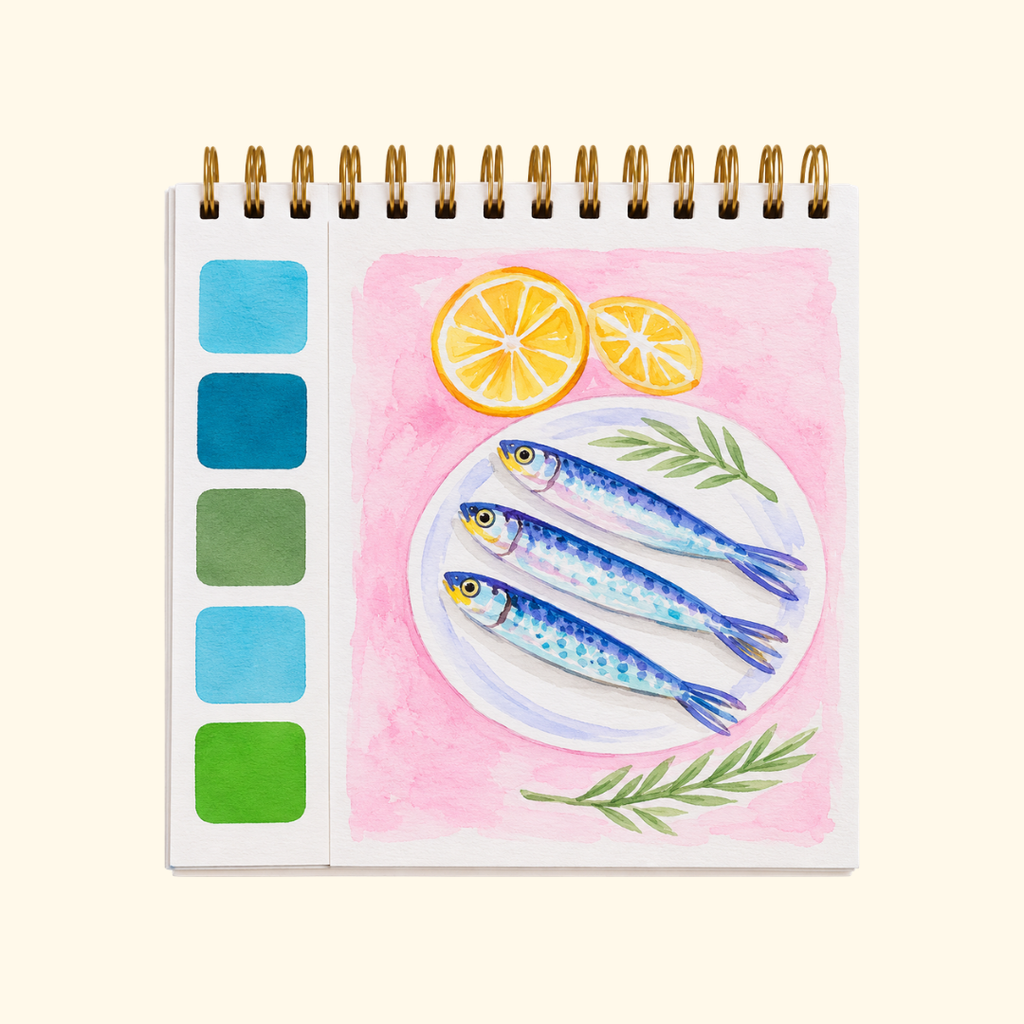 Mediterranean Watercolour Travel Book by La Petite Epicerie showing a colourful hand-painted illustration of a Mediterranean coastal scene with blue striped beach umbrellas and a built-in watercolour palette.