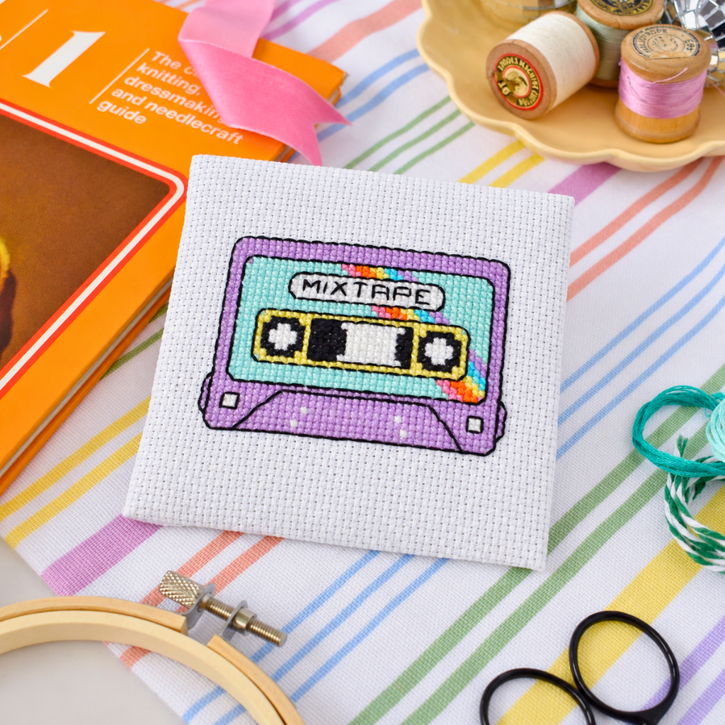Completed mixtape cross stitch design styled with colourful stationery and craft supplies.