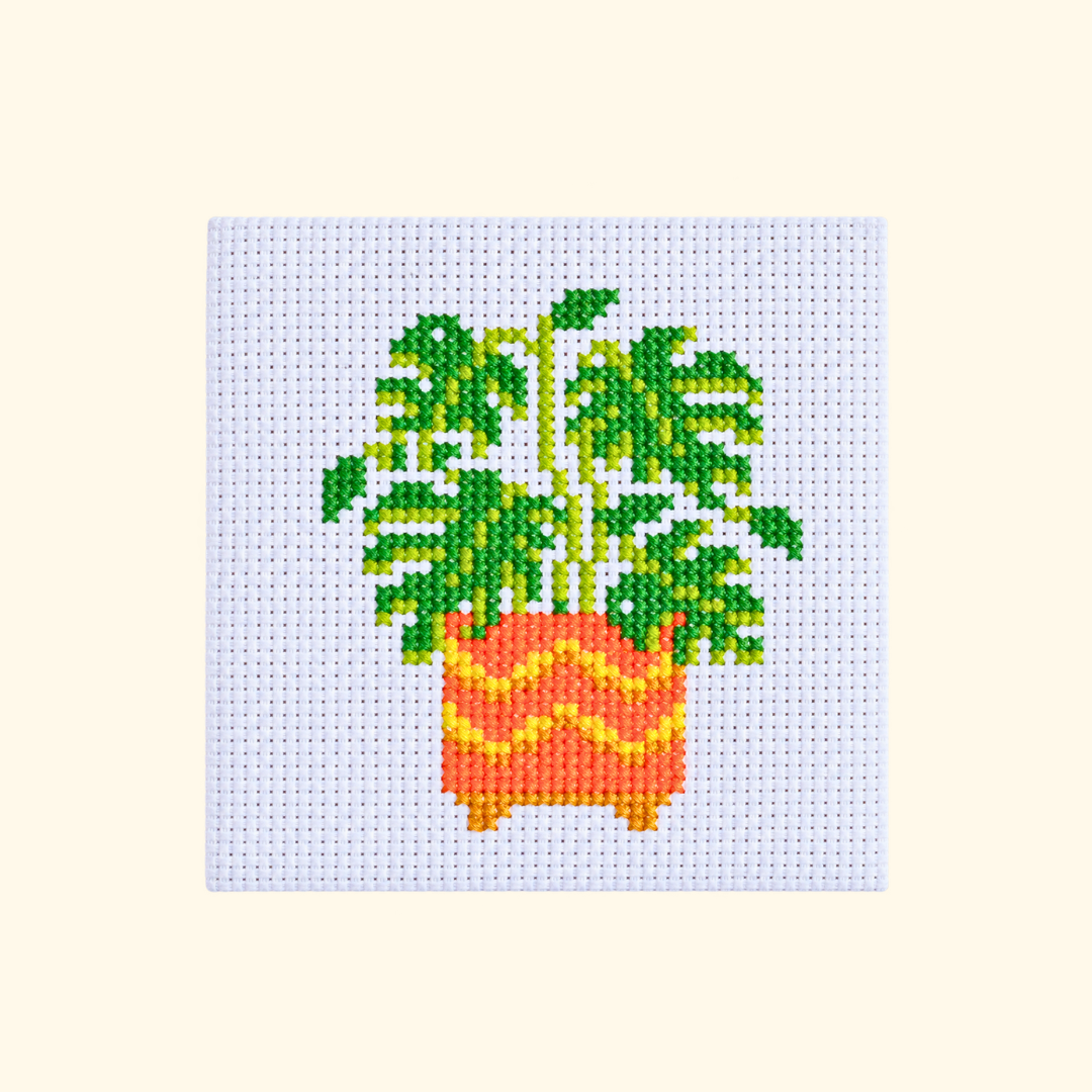 Completed monstera plant cross stitch design in a colourful orange and yellow pot.