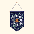Felt wall hanging featuring an orange moth surrounded by moon phases, leaves and stars on a dark blue background