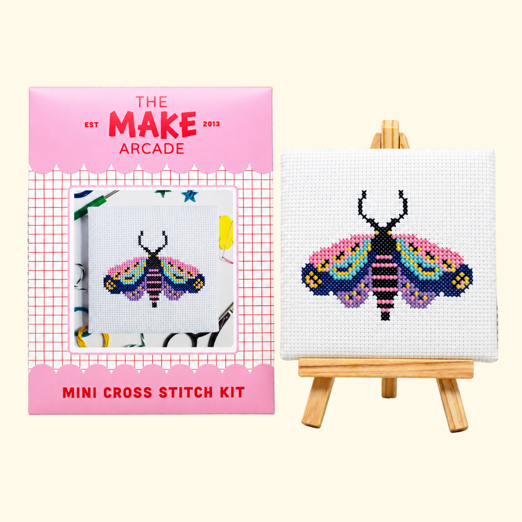 The Make Arcade Moth Mini Cross Stitch Kit beside the completed moth design on a miniature easel.