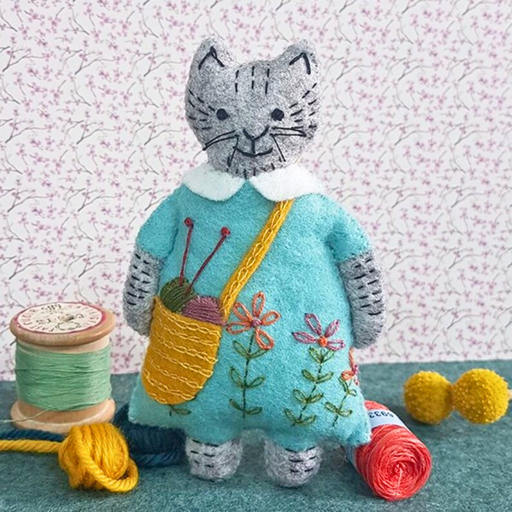 Close up of the completed Mrs Cat ornament from the Mrs Cat Felt Craft Kit by Corinne Lapierre displayed with colourful yarn and sewing notions.