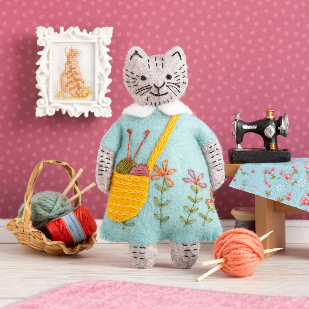 Completed Mrs Cat ornament from the Mrs Cat Felt Craft Kit by Corinne Lapierre displayed with yarn, sewing accessories and miniature craft room props.