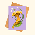 Mushroom Snuggles greeting card shown with a matching kraft envelope, featuring a whimsical mother mushroom cuddling her baby beneath delicate lily of the valley flowers.