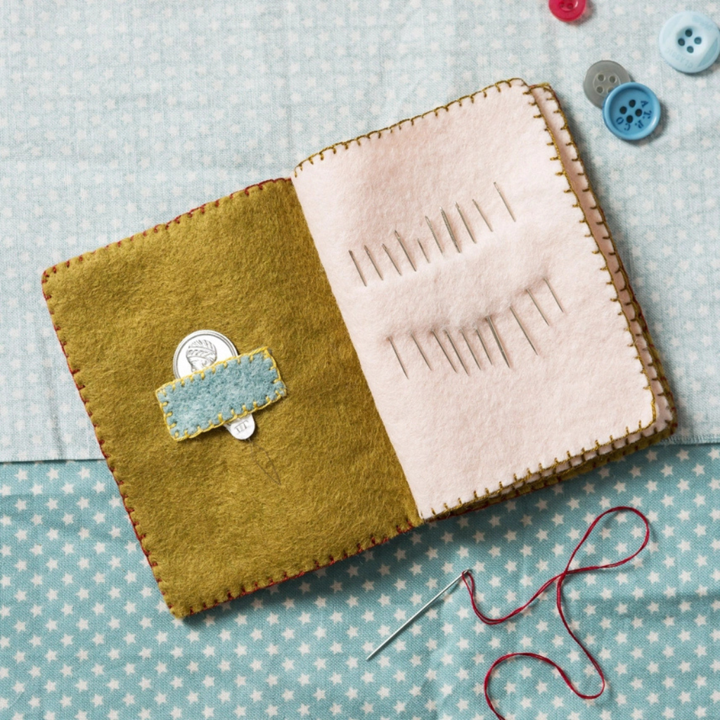 Open handmade felt needle case showing internal felt pages for safely storing sewing needles and pins.