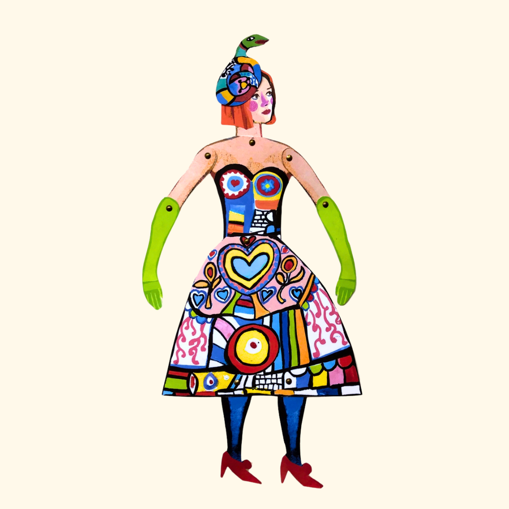 Completed Niki de Saint Phalle articulated paper puppet wearing a vibrant patterned outfit against a white background.