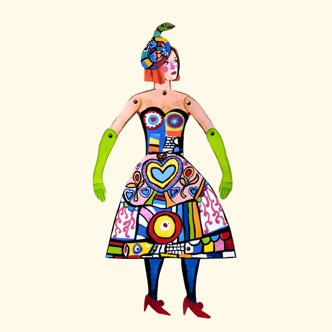 Completed Niki de Saint Phalle articulated paper puppet wearing a vibrant patterned outfit against a white background.