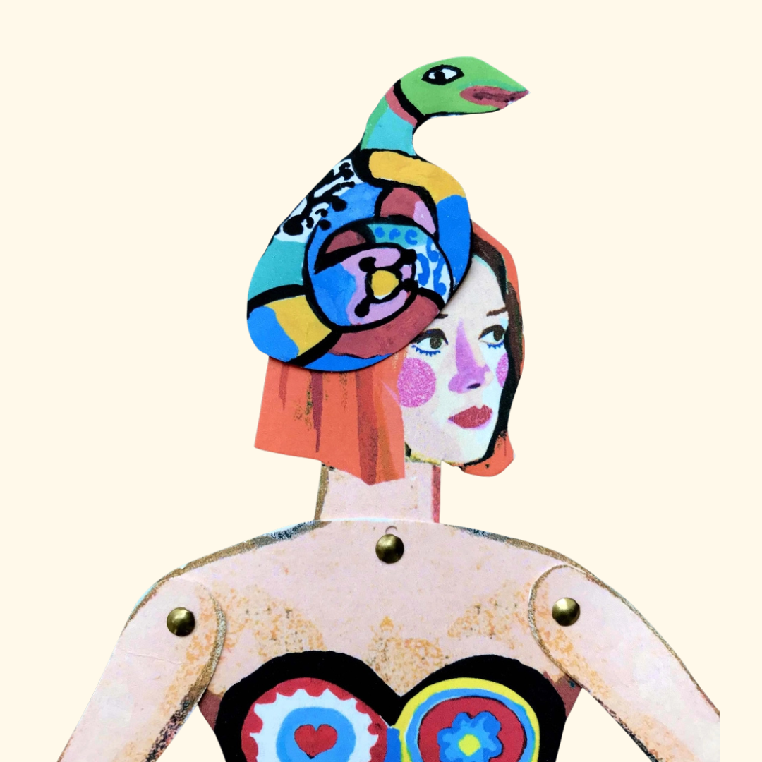 Close-up of the Niki de Saint Phalle paper puppet featuring a colourful snake headdress and illustrated dress.