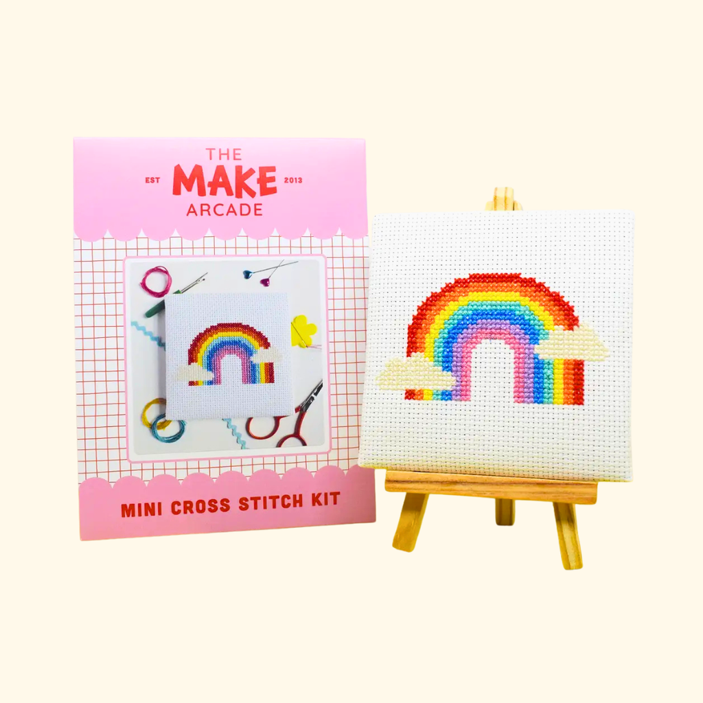 Over The Rainbow Mini Cross Stitch Kit by The Make Arcade with packaging and finished stitched design on a mini easel.