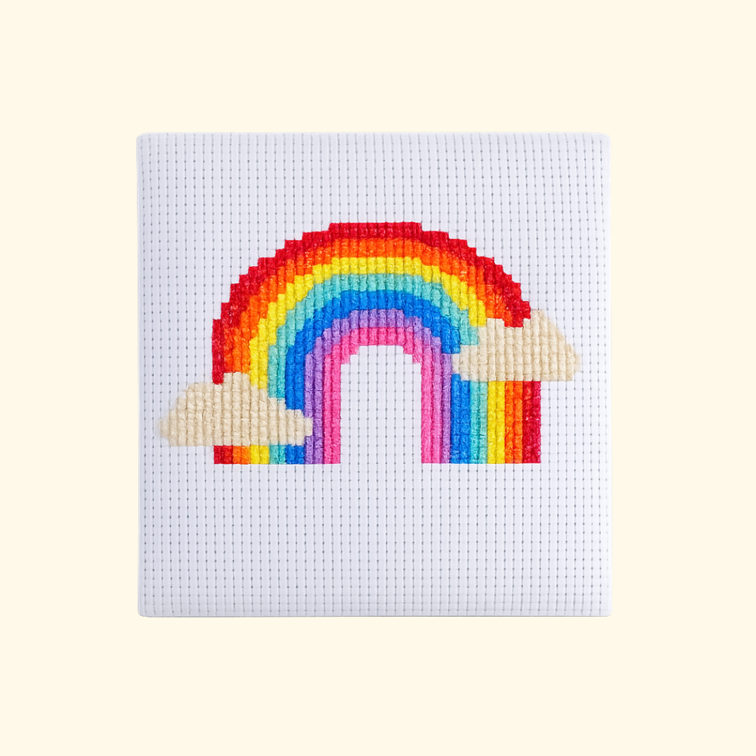 Completed Over The Rainbow Mini Cross Stitch Kit featuring a colourful rainbow with fluffy clouds by The Make Arcade.