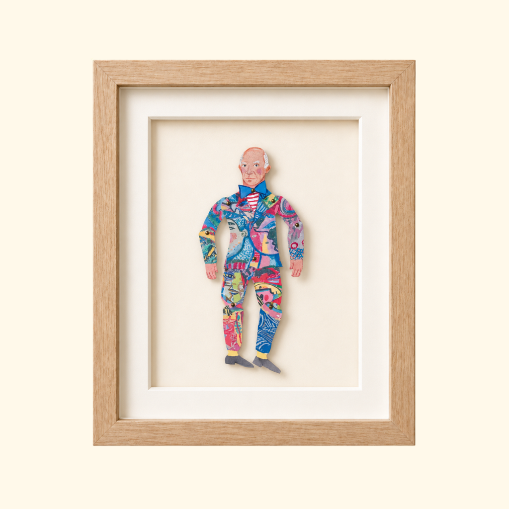 Framed Pablo Picasso paper puppet wearing a brightly patterned suit and striped shirt.