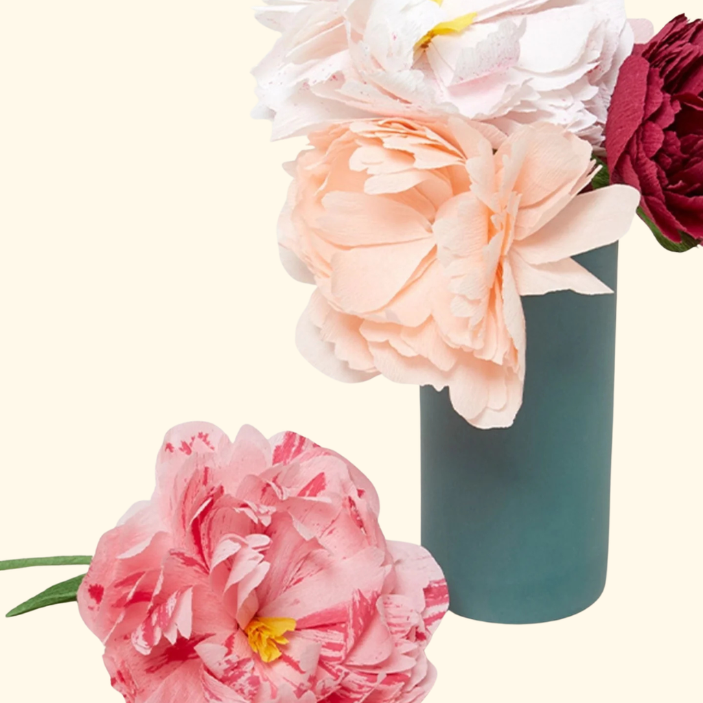 Completed paper flowers in pink and burgundy arranged in a blue vase