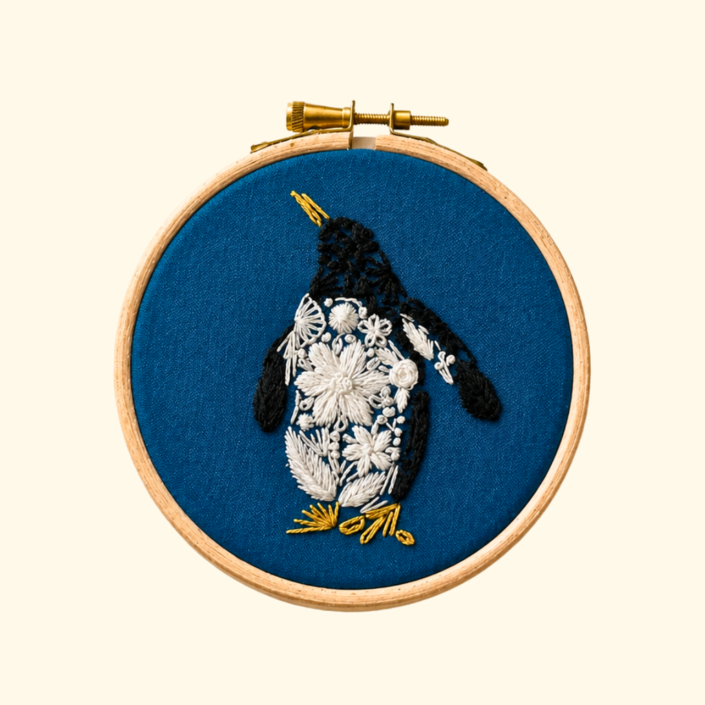 Completed Penguin Mini Embroidery Kit by Nest Embirdery featuring a hand-stitched penguin on navy fabric.
