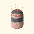 Handmade embroidered felt pincushion with pink base, decorative stitching and colourful sewing pins