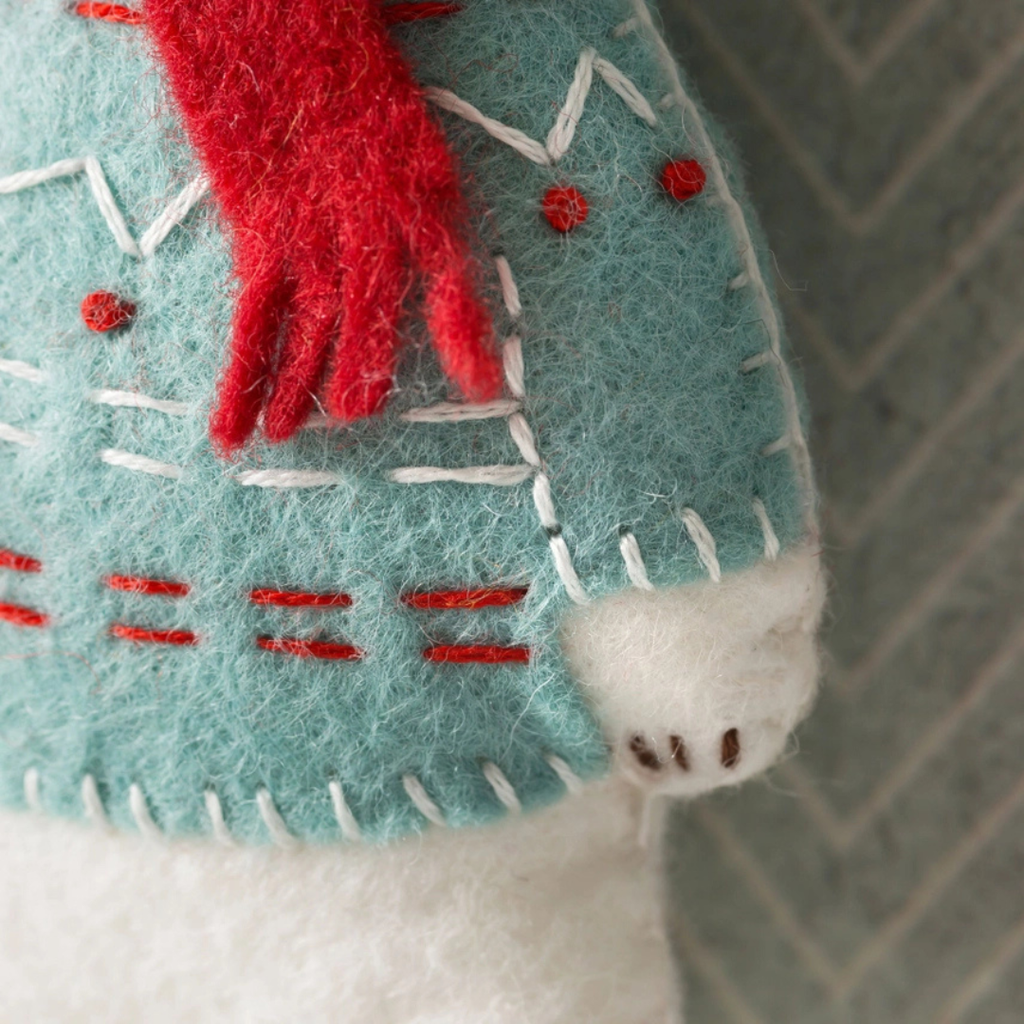 Close-up of the polar bear felt craft showing the stitched patterned jumper, red scarf and hand-sewn details.