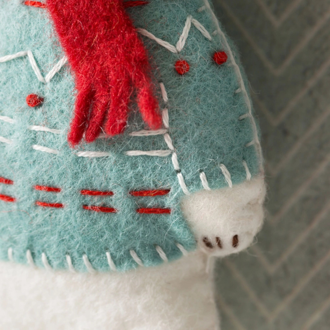 Close-up of the polar bear felt craft showing the stitched patterned jumper, red scarf and hand-sewn details.