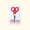 Poppy red Cotton Clara embroidery scissors with compact pointed blades, presented on branded product packaging.