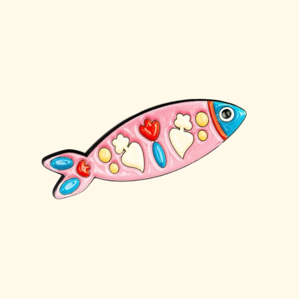 Colourful enamel Portuguese sardine magnetic needle minder by Unwind Studio on a cream background.