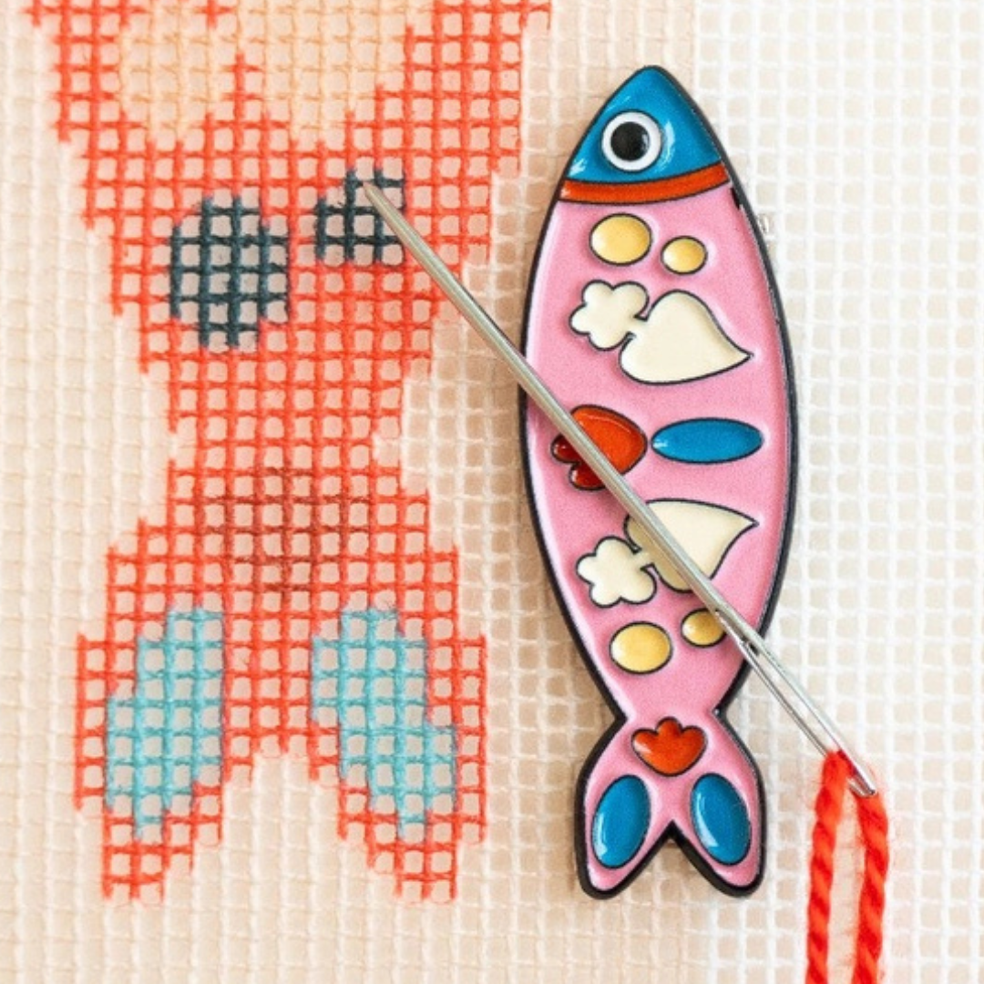 Portuguese Sardine Magnetic Needle Minder holding a needle on a needlepoint canvas during stitching. 