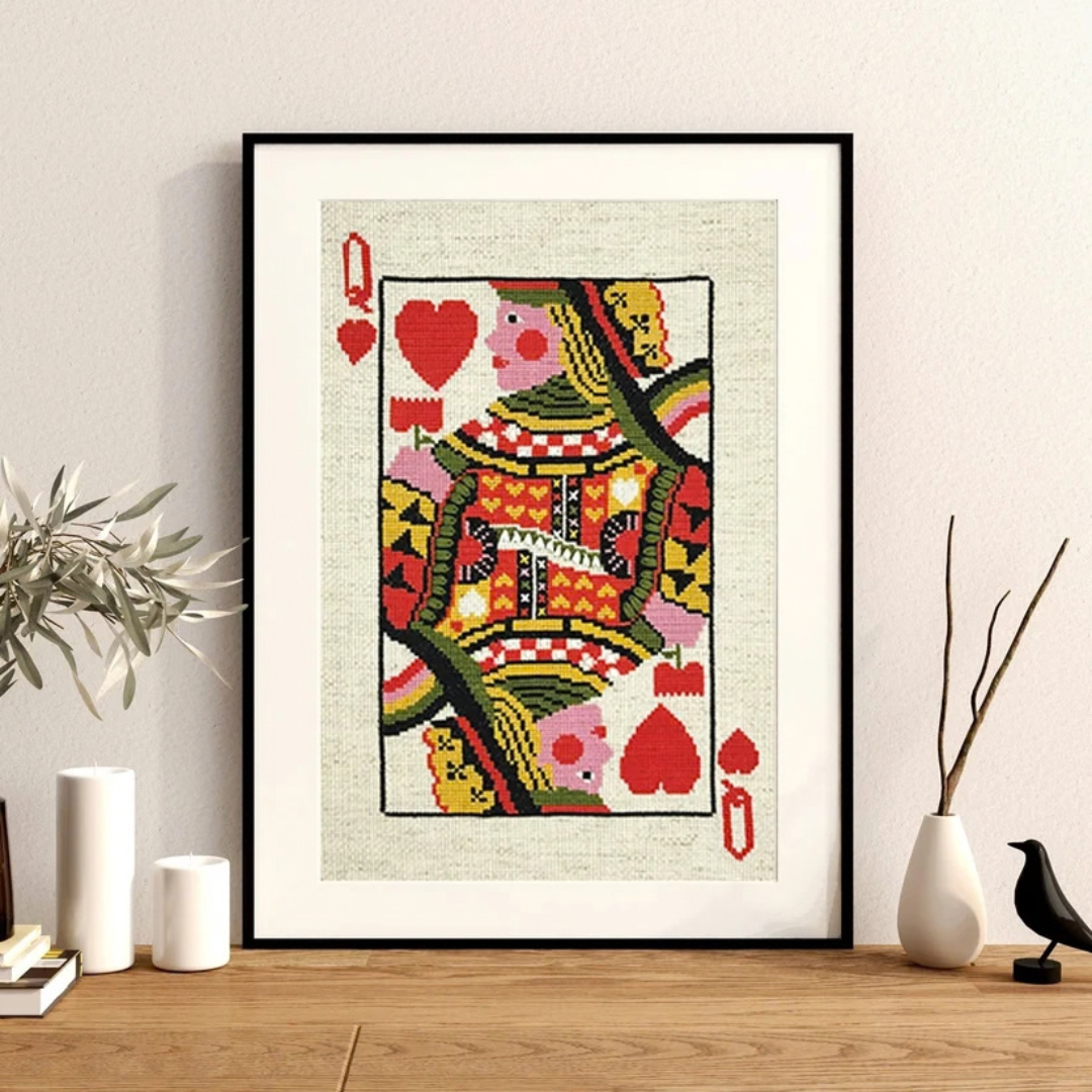 Queen of Hearts cross stitch by Budgiegoods displayed in a black frame on a styled shelf.