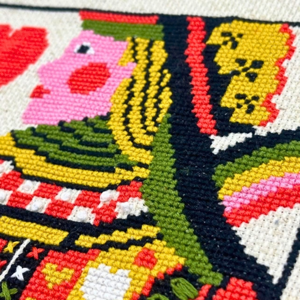 Close-up of the Queen of Hearts cross stitch by Budgiegoods, showing colourful stitched details and texture.