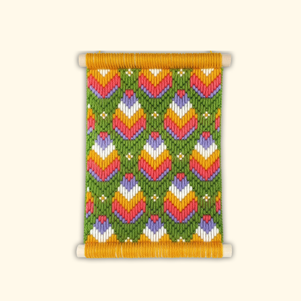 Completed Retro Blooms bargello wall hanging featuring colourful geometric floral patterns in pink, orange, green and lavender
