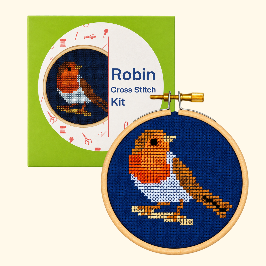 Paraffle Robin Redbreast Mini Cross Stitch Kit packaging beside the finished bird design in a wooden hoop.