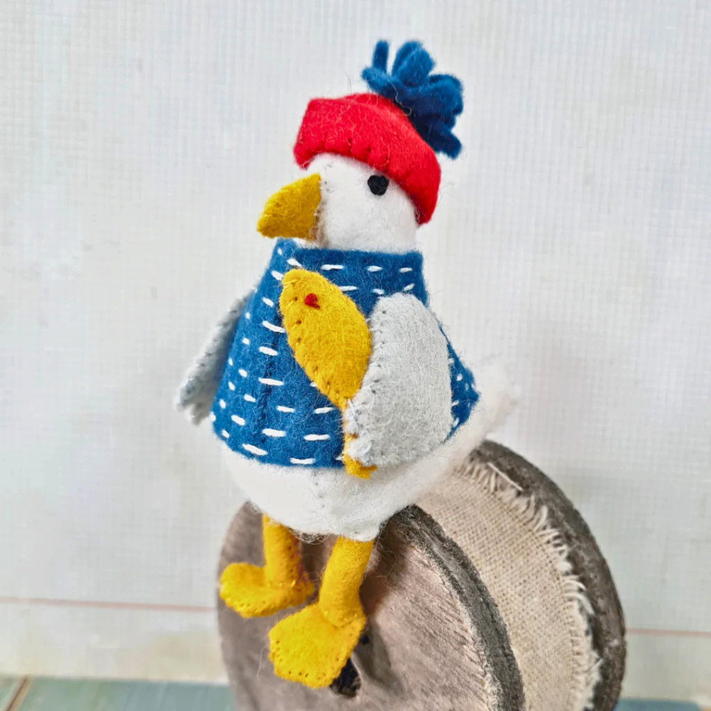 Completed Sam the Seagull felt craft kit perched on a spool of thread displaying the side profile.
