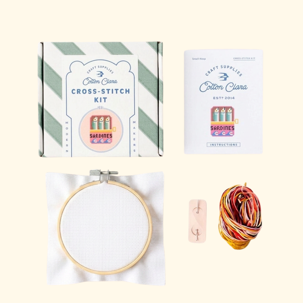 Contents of the Cotton Clara Sardines Cross Stitch Kit including hoop, Aida fabric, threads, needle and instructions.