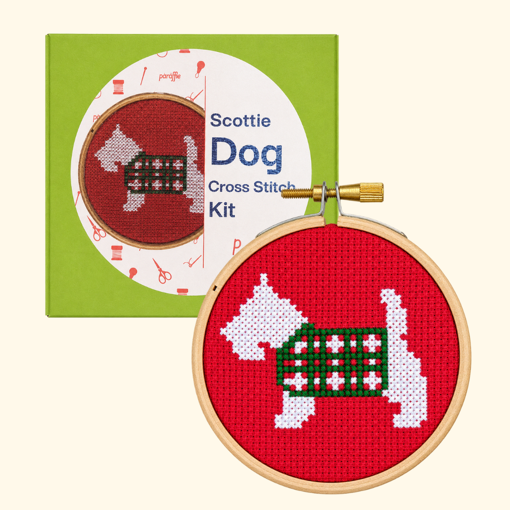 Paraffle Scottie Dog Mini Cross Stitch Kit packaging beside the finished Scottish terrier design in a wooden hoop.