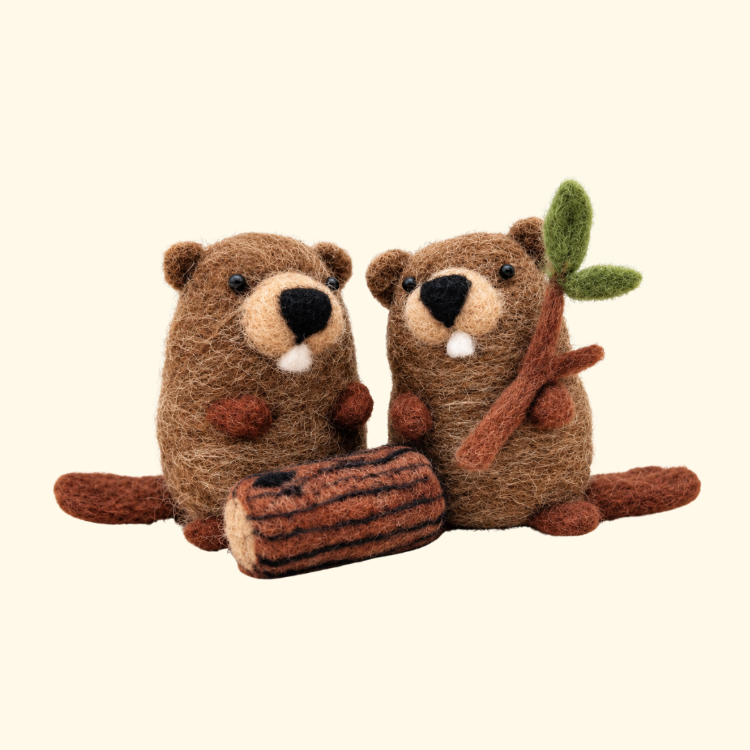 Two handmade brown wool beavers with little ears, flat tails and a wooden log, created using the Bergin And Bath Set Of 2 Beavers Needle Felting Kit.